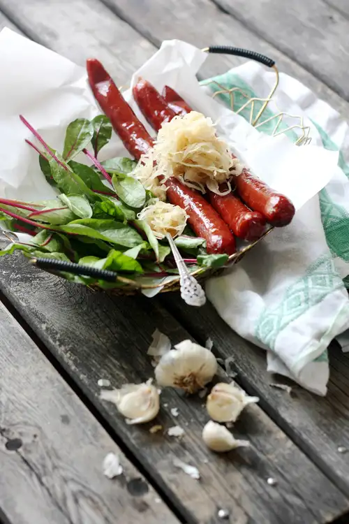 Tre korvar på en tallrik med en gaffel och sallad.